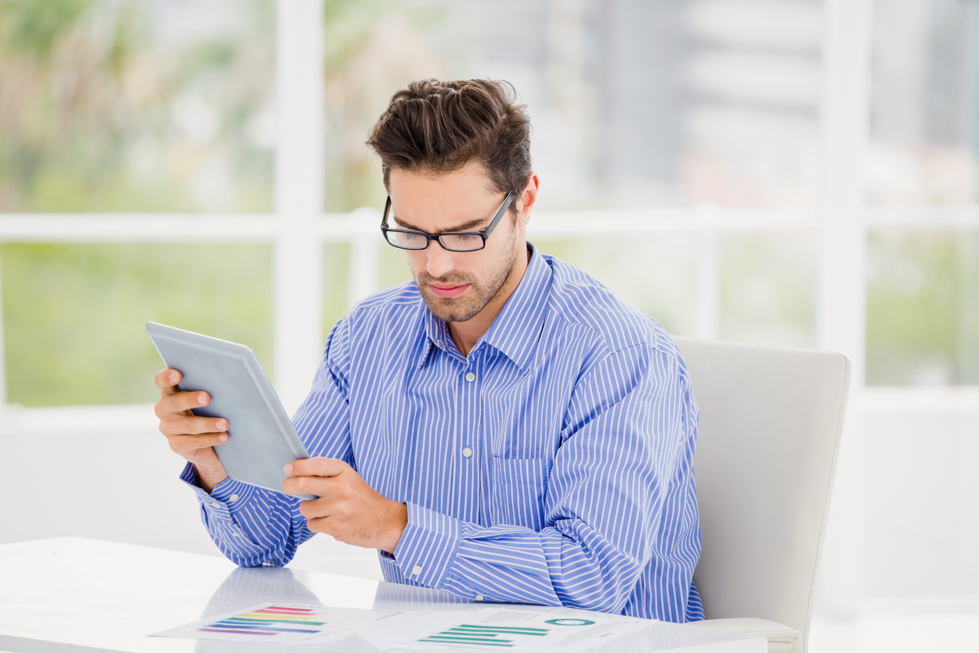 Person prüft Finanzen mit Tablet und Notizen